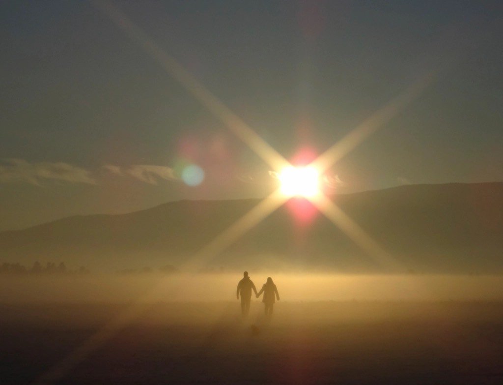 Pareja de la mano frente al atardecer, representando el programa Construyendo juntos